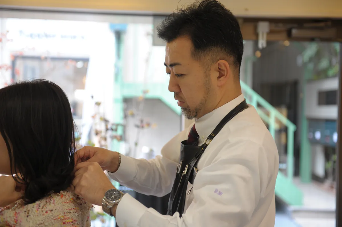店頭でネックレスを試着し、襟元を合わせる様子