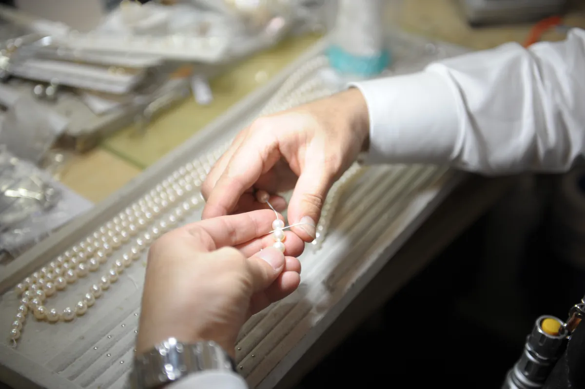 真珠ネックレスの金具を両手で確かめる様子